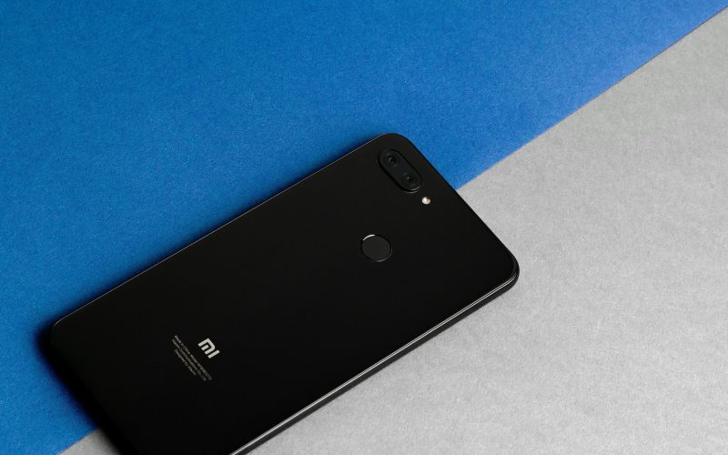 Modern black MI smartphone placed on a blue and gray background, showcasing technology elegance.